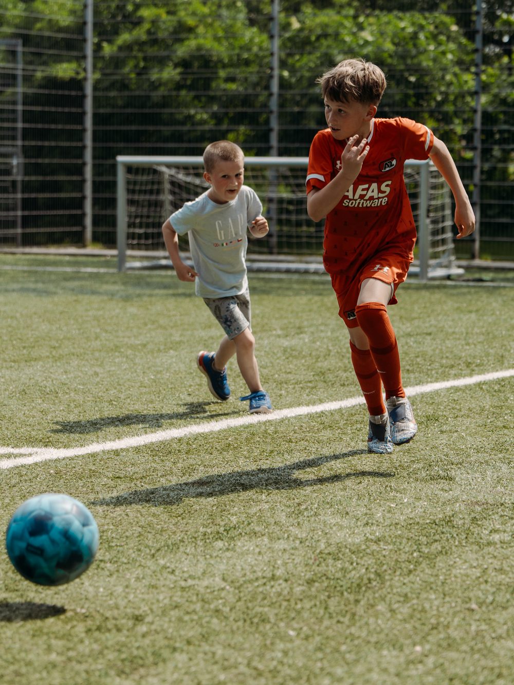 Twee jongens rennen achter een bal aan op het veld