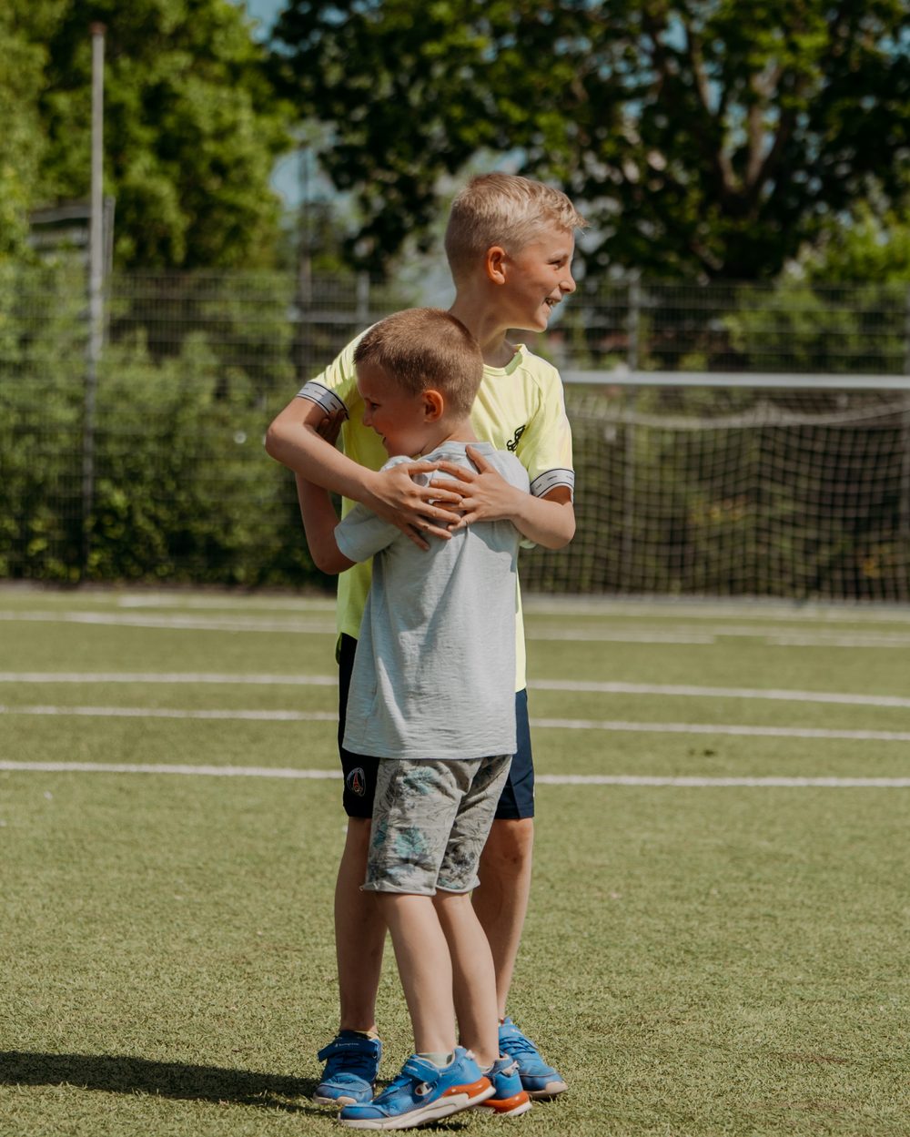 Twee jongens met een arm om elkaar heen op het veld