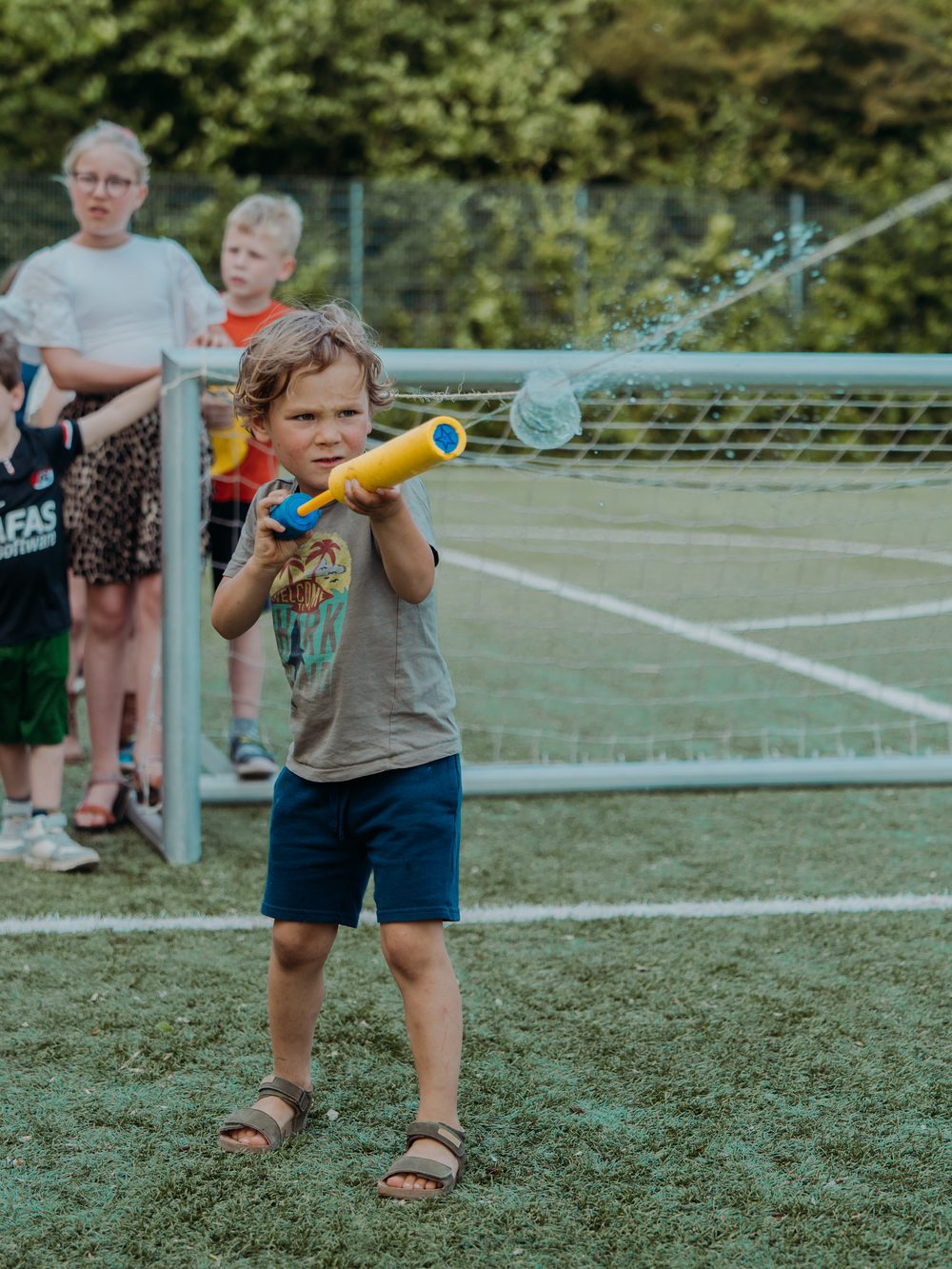 Jongen doet mee aan een waterspel op het veld